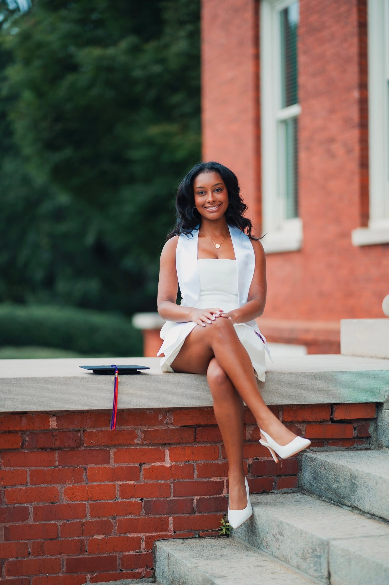 Madison seated on brick steps in her graduation dress